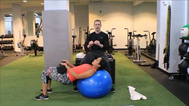 Dr. Brookbush instructs model, Melissa Ruiz, on how to perform the &#34;ultimate glute bridge&#34; using a stability ball, band resistance around the knees and load via a dumbell.